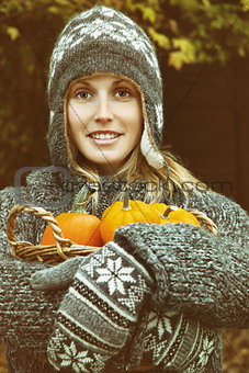 Young woman holding a basket of pumpkins 