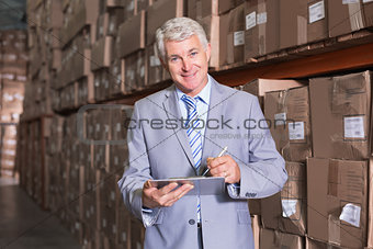 Warehouse manager writing on clipboard