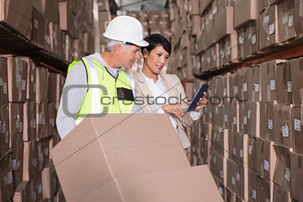 Warehouse worker moving boxes on trolley talking to manager