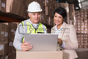 Warehouse worker and manager looking at laptop