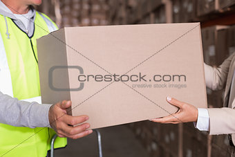 Warehouse worker and manager passing a box