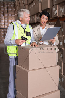 Warehouse worker scanning box with manager