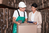 Warehouse worker scanning box with manager holding tablet pc
