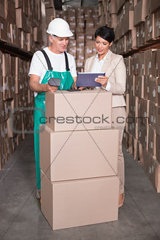 Warehouse worker scanning box with manager holding tablet pc