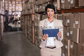 Pretty warehouse manager smiling at camera using tablet pc