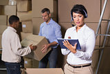 Pretty warehouse manager using tablet during busy period