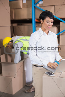 Pretty warehouse manager using laptop