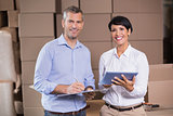Pretty warehouse manager using tablet pc with colleague