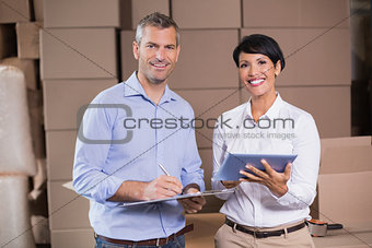 Pretty warehouse manager using tablet pc with colleague