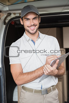 Delivery driver smiling at camera beside his van