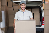 Delivery driver smiling at camera holding box