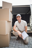 Delivery driver smiling at camera with pile of packages