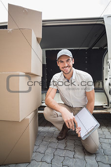 Delivery driver smiling at camera with pile of packages