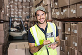 Warehouse worker smiling at camera with clipboard