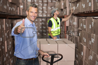 Warehouse manager smiling at camera with trolley