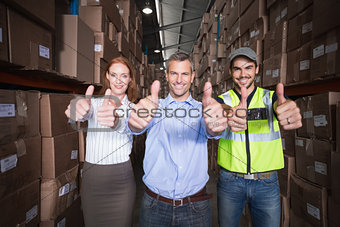 Warehouse team smiling at camera showing thumbs up