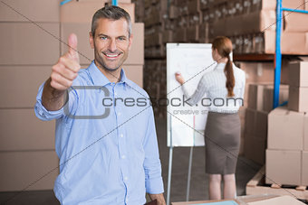 Warehouse manager smiling at camera showing thumbs up