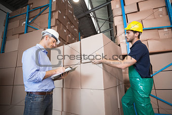 Warehouse worker loading up a pallet with manager