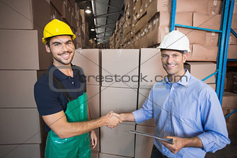 Warehouse worker loading up a pallet with manager