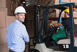 Warehouse manager smiling at camera with delivery in background