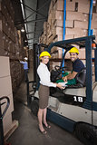 Warehouse manager smiling at camera with forklift driver