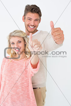 Happy young couple gesturing thumbs up