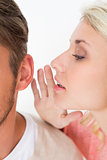Woman whispering secret into a man's ear