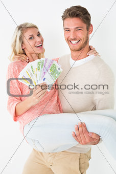 Young man carrying cheerful woman with banknotes