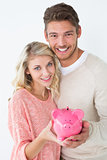 Attractive young couple holding piggybank
