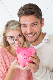 Attractive young couple holding piggybank