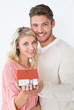 Attractive young couple holding mini house