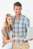 Portrait of happy young couple using laptop