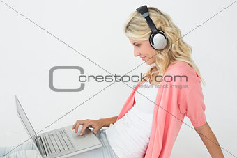 Young woman using laptop while listening to music