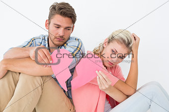 Young couple holding two halves of broken heart