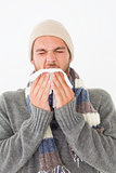 Young man in warm clothing sneezing
