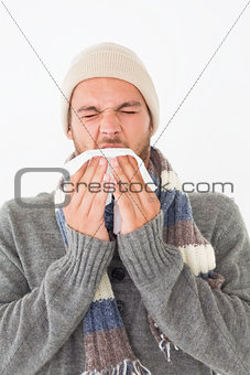 Young man in warm clothing sneezing