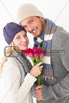 Attractive couple in warm clothing holding flowers