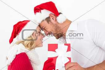 Attractive couple wearing santa hats with gift
