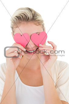 Smiling woman holding hearts over her eyes