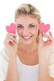 Smiling young woman holding pink hearts