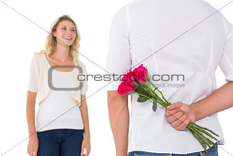 Man hiding bouquet of roses from woman