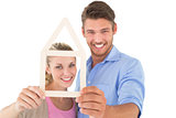 Attractive young couple looking through house outline