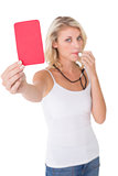 Young woman blowing whistle and holding red card