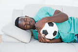 Football fan hugging ball on couch