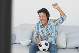 Soccer fan cheering while watching tv