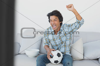 Soccer fan cheering while watching tv