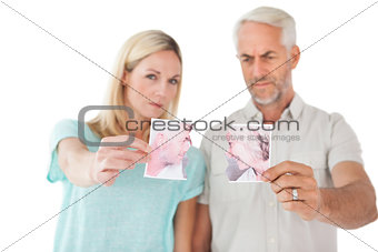 Couple holding two halves of torn photograph