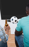 Two soccer fans watching tv