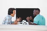 Two excited soccer fans watching tv