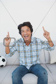 Happy soccer fan cheering while watching tv